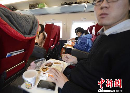 资料图：图为动车组乘客在品尝列车提供的餐食。中新社发 侯宇 摄