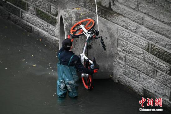资料图：一辆共享单车被扔进成都锦江，工作人员冒着寒冬下水将其打捞上岸。张浪 摄